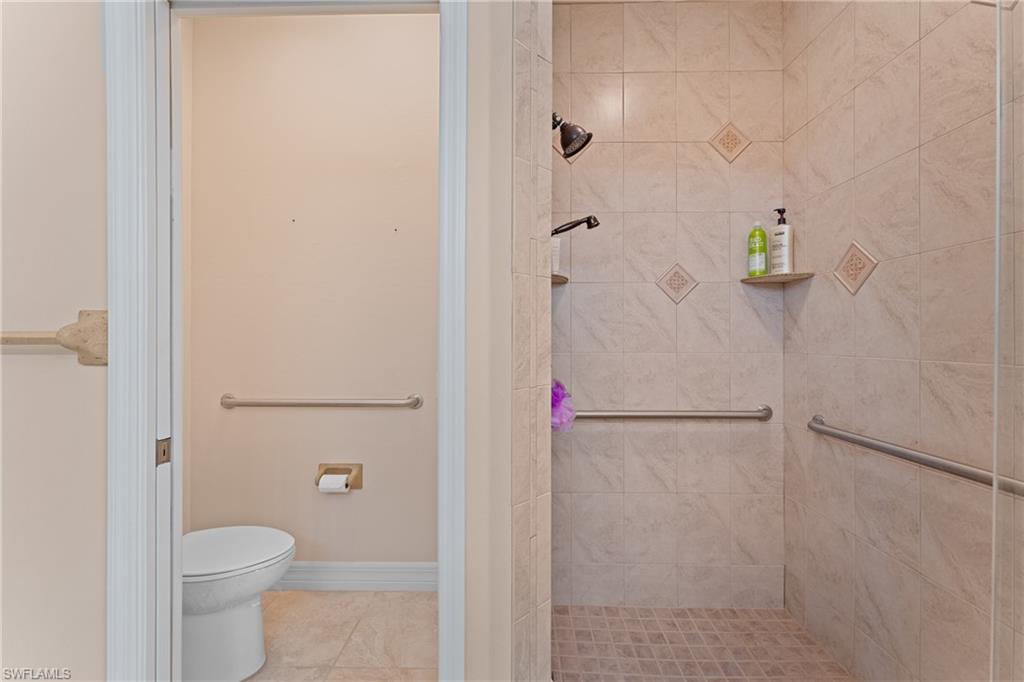 Bathroom featuring tile patterned floors, toilet, and a tile shower