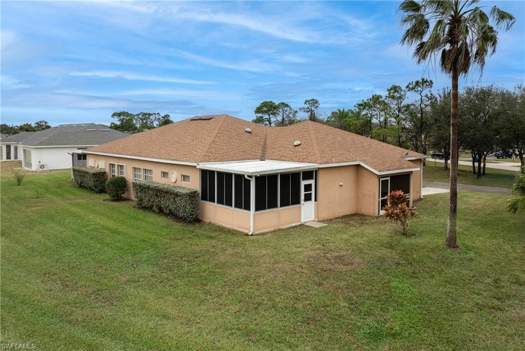 Rear view of house featuring a sunroom and a lawn