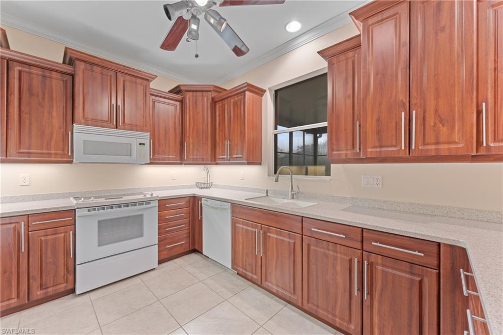Kitchen featuring light tile patterned floors, ornamental molding, sink, and white appliances