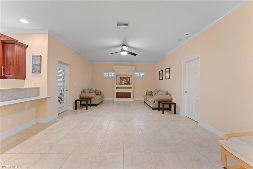 Living area featuring ceiling fan, light tile patterned flooring, and crown molding