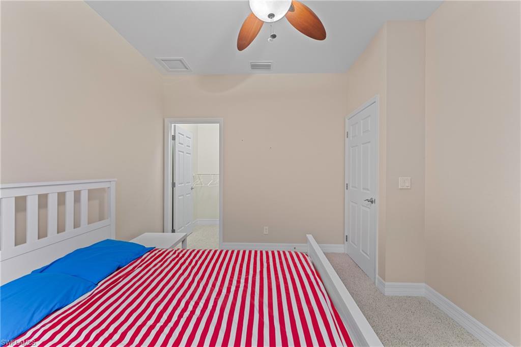 Unfurnished bedroom with ceiling fan, light colored carpet, a closet, and a spacious closet