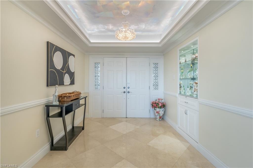 Foyer entrance with a chandelier and a raised ceiling