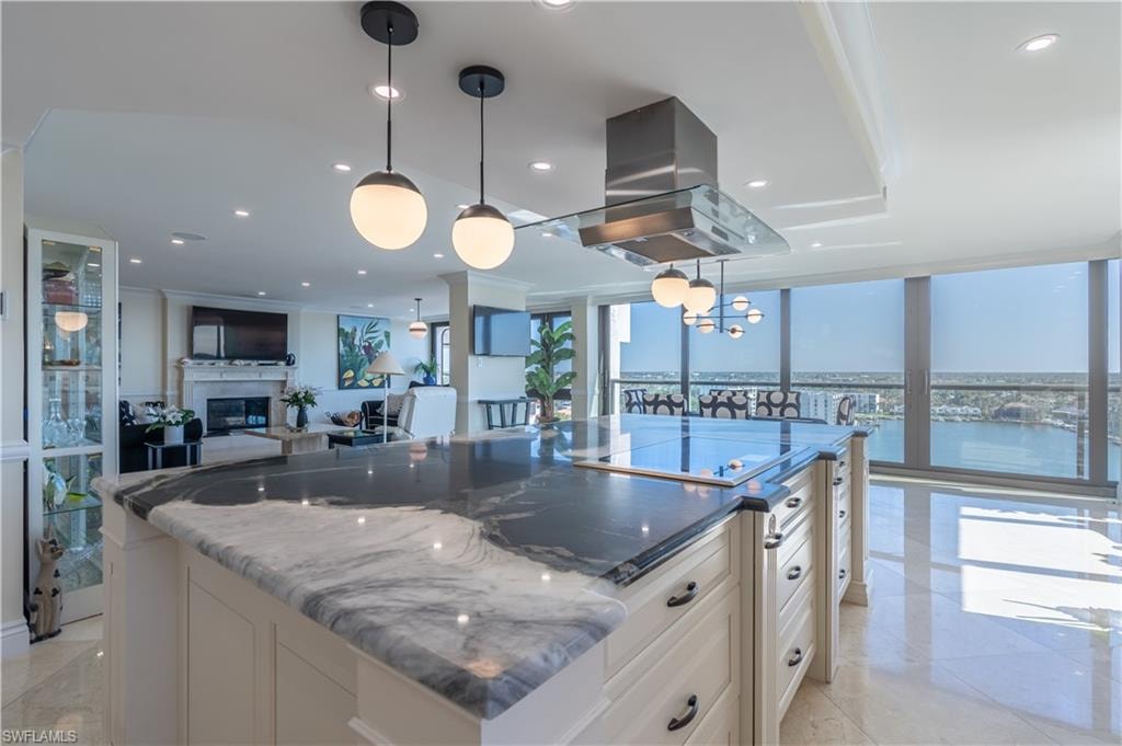 Kitchen with dark stone countertops, a water view, island range hood, and decorative light fixtures