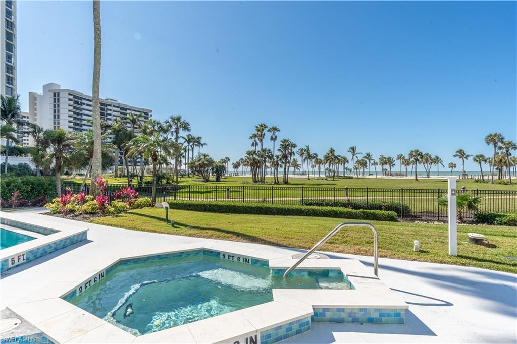 View of pool with a hot tub and a yard