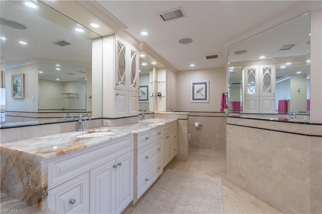 Primary Bathroom featuring tile walls, vanity, crown molding, and tile patterned flooring