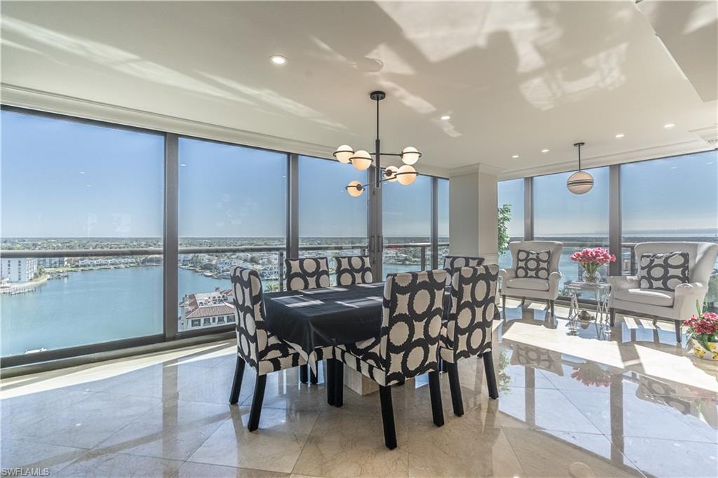 Dining area with a notable chandelier, a water view, and floor to ceiling windows