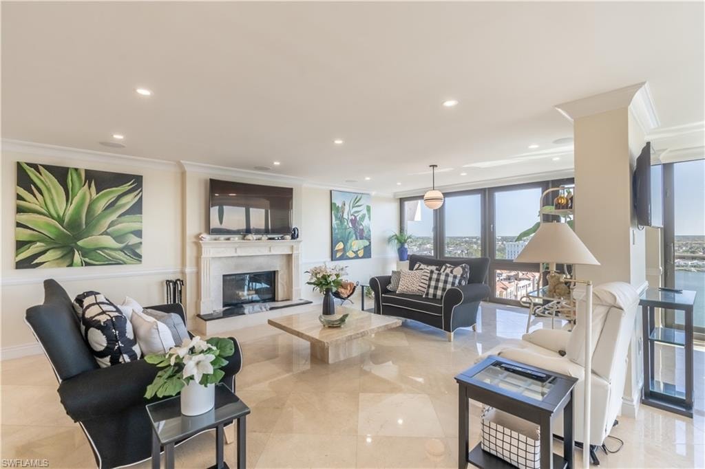 Living room with baseboards, a premium fireplace, ornamental molding, and recessed lighting