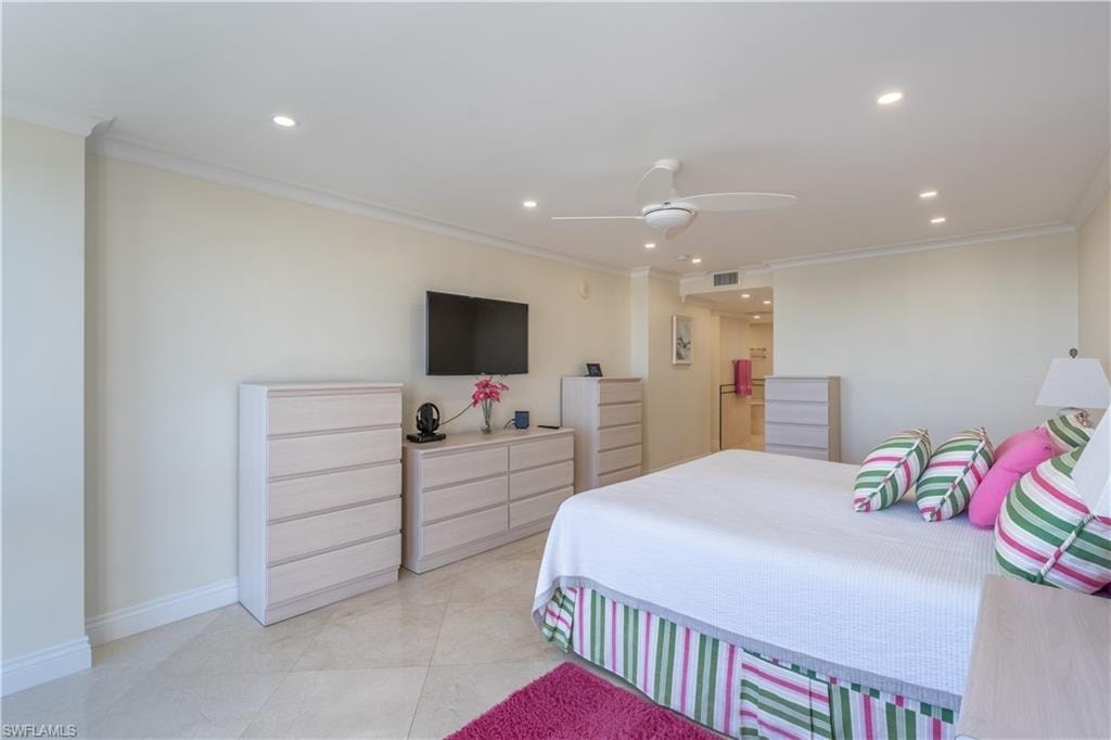 Primary  bedroom with ornamental molding, ceiling fan, and light tile patterned floors