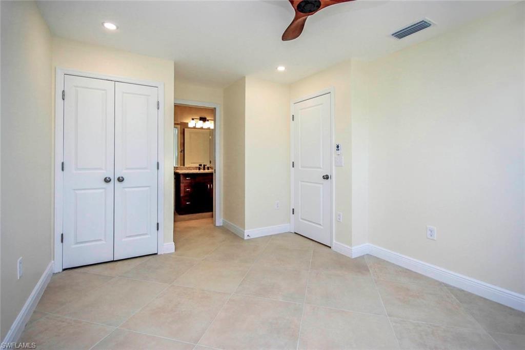 Unfurnished bedroom with a closet, connected bathroom, ceiling fan, and light tile patterned floors