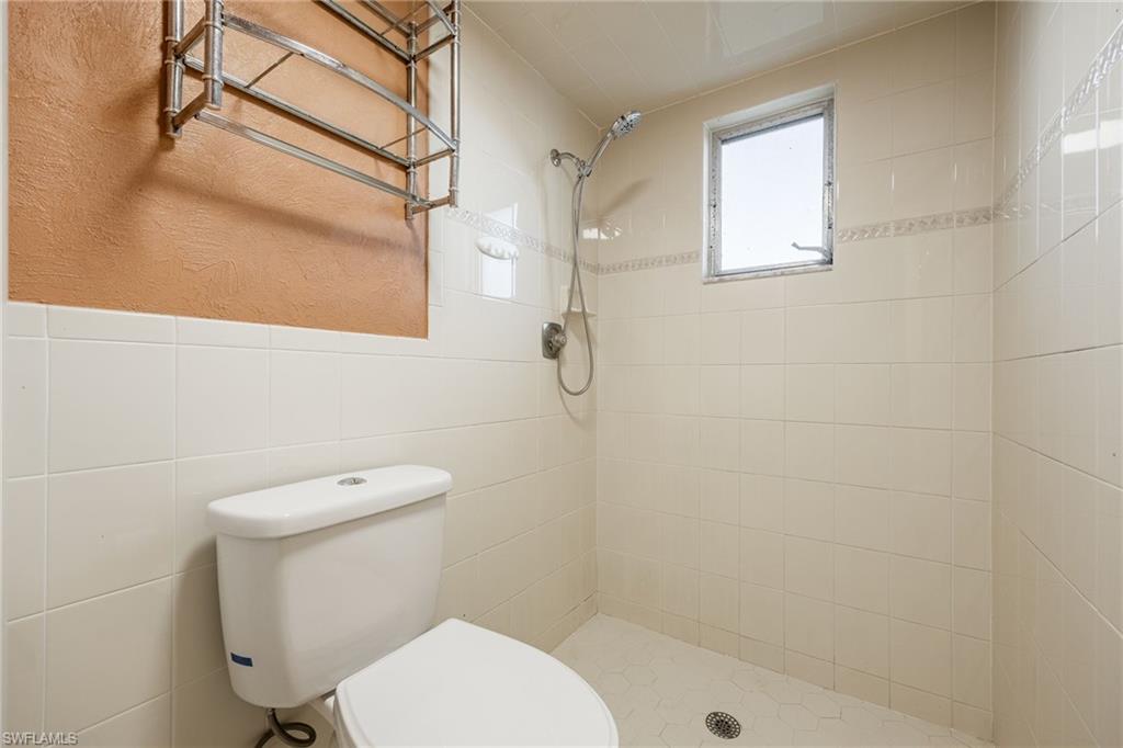 Bathroom with toilet, tile walls, and a tile shower