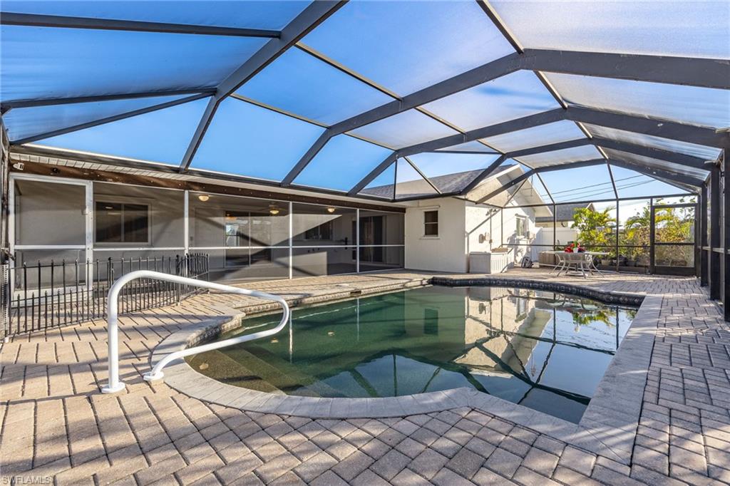 View of pool with a patio area and glass enclosure