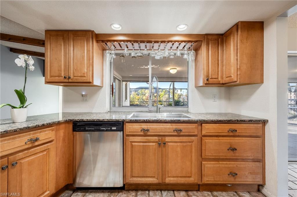 Kitchen featuring dark stone countertops, sink, and stainless steel dishwasher