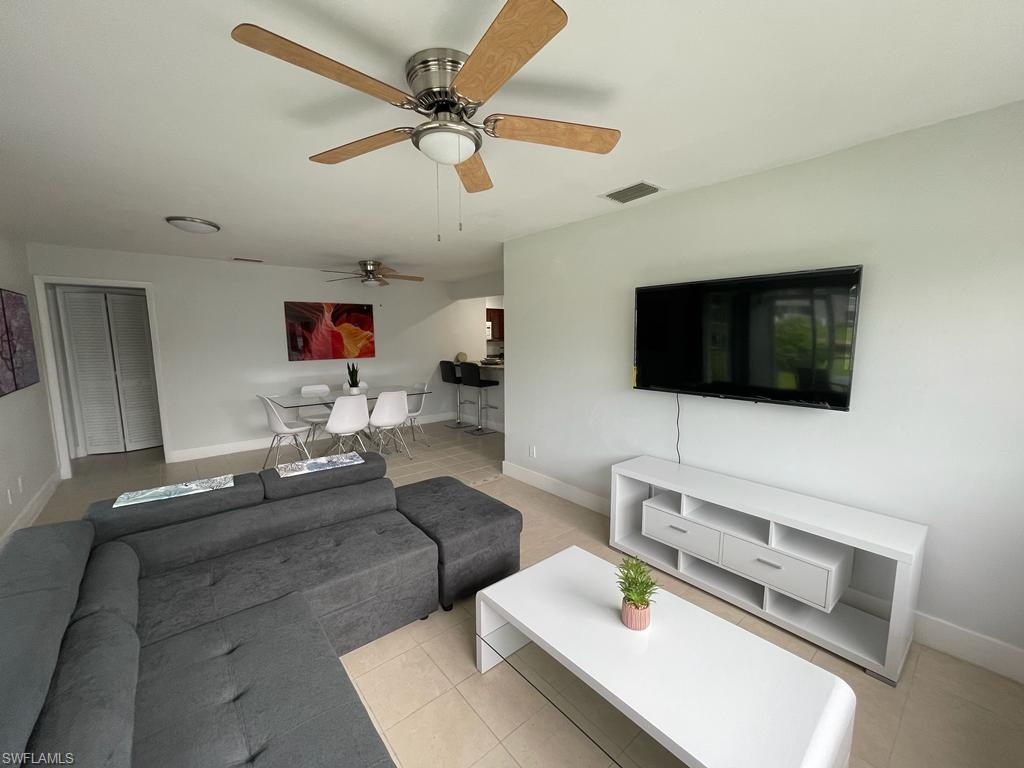 Living room with ceiling fan and light tile patterned floors