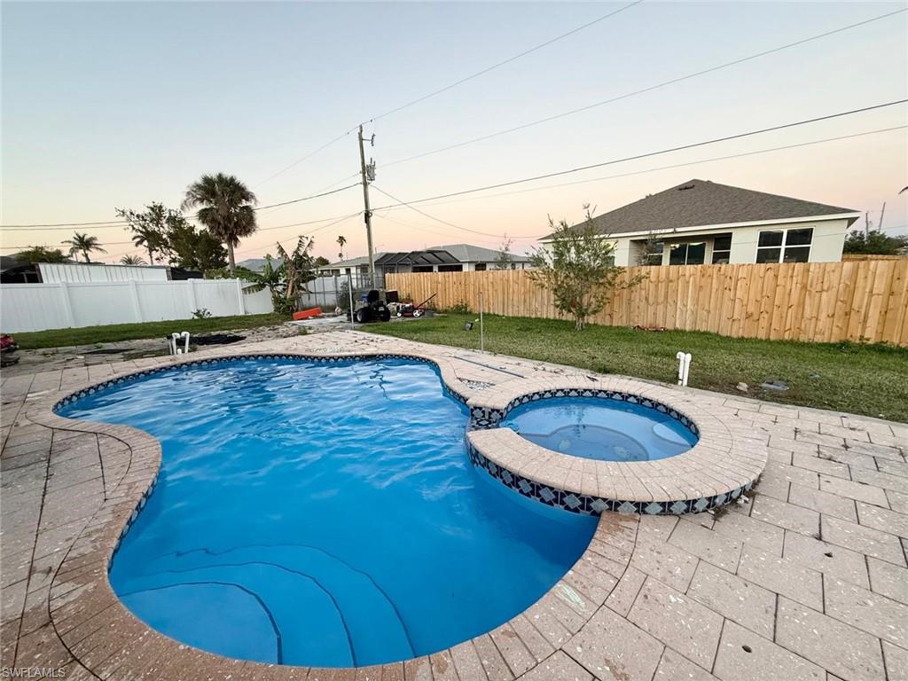 Pool at dusk featuring an in ground hot tub and a patio area