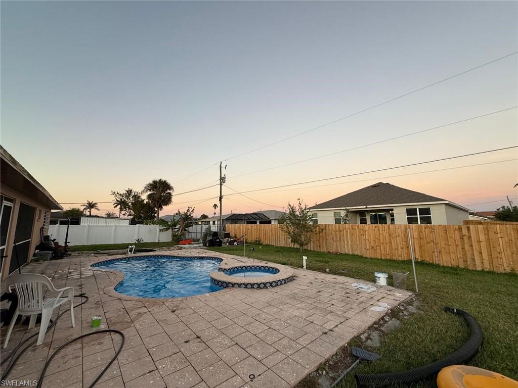 Pool at dusk with a patio and an in ground hot tub