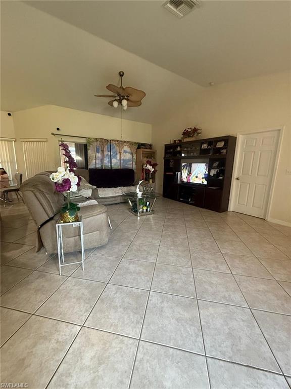 Unfurnished living room with vaulted ceiling, tile patterned floors, and ceiling fan