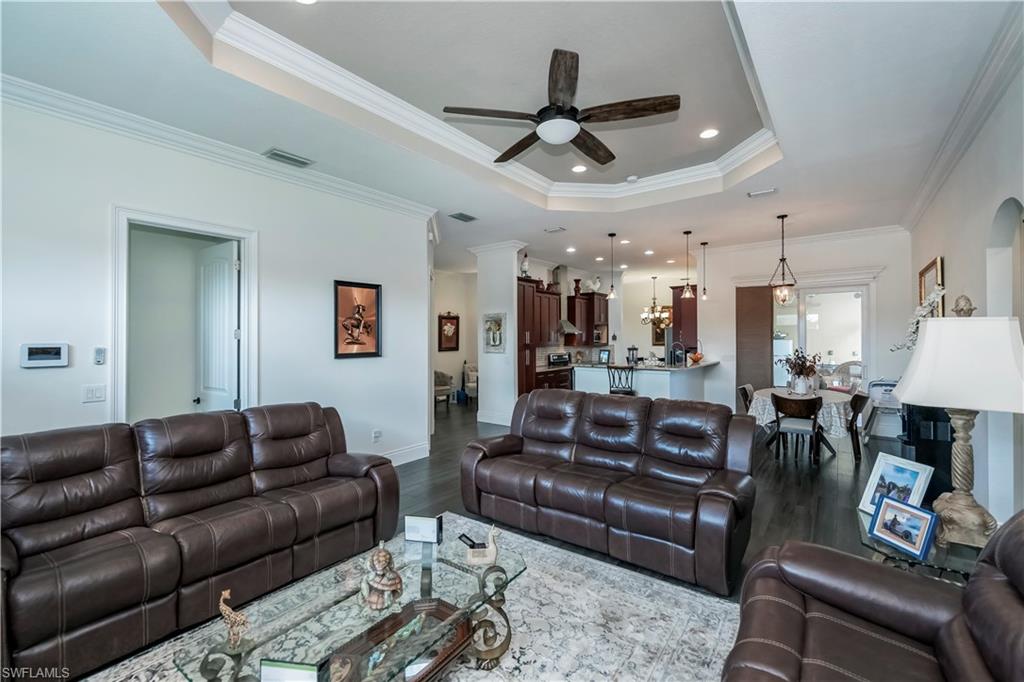 Living room featuring crown molding, a tray ceiling, ceiling fan, and hardwood / wood-style flooring