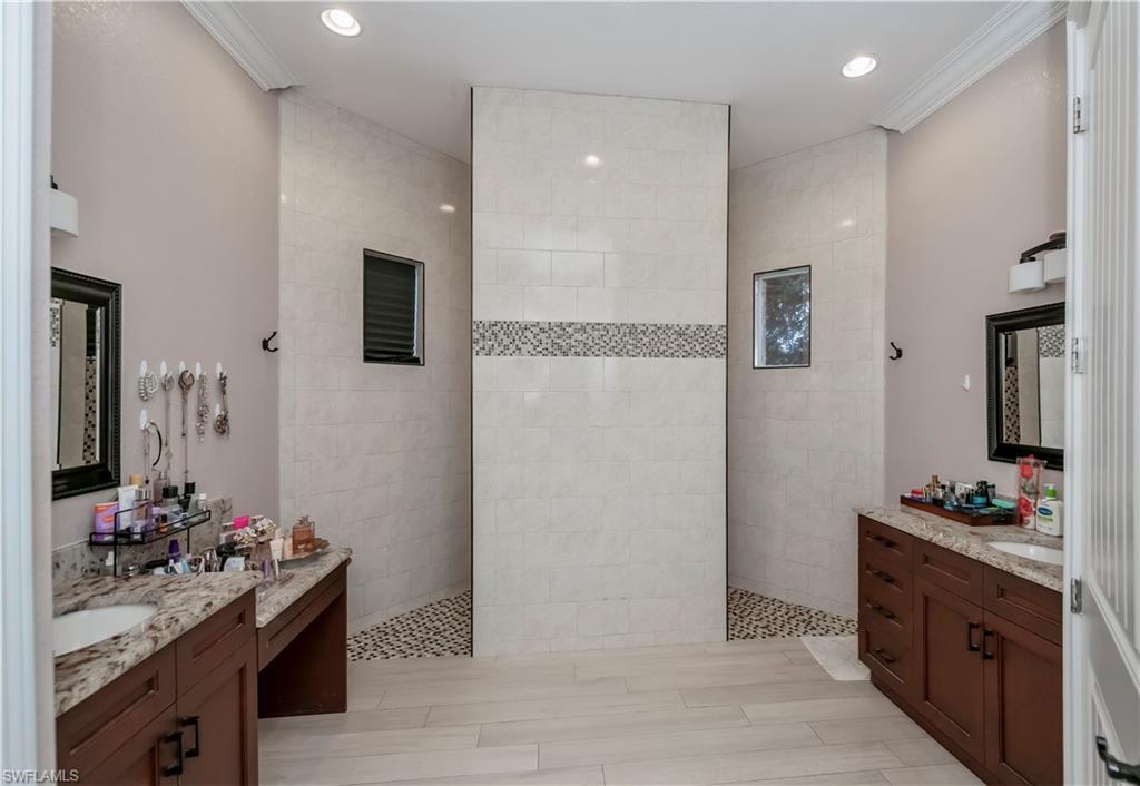 Bathroom featuring tiled shower, vanity, and ornamental molding