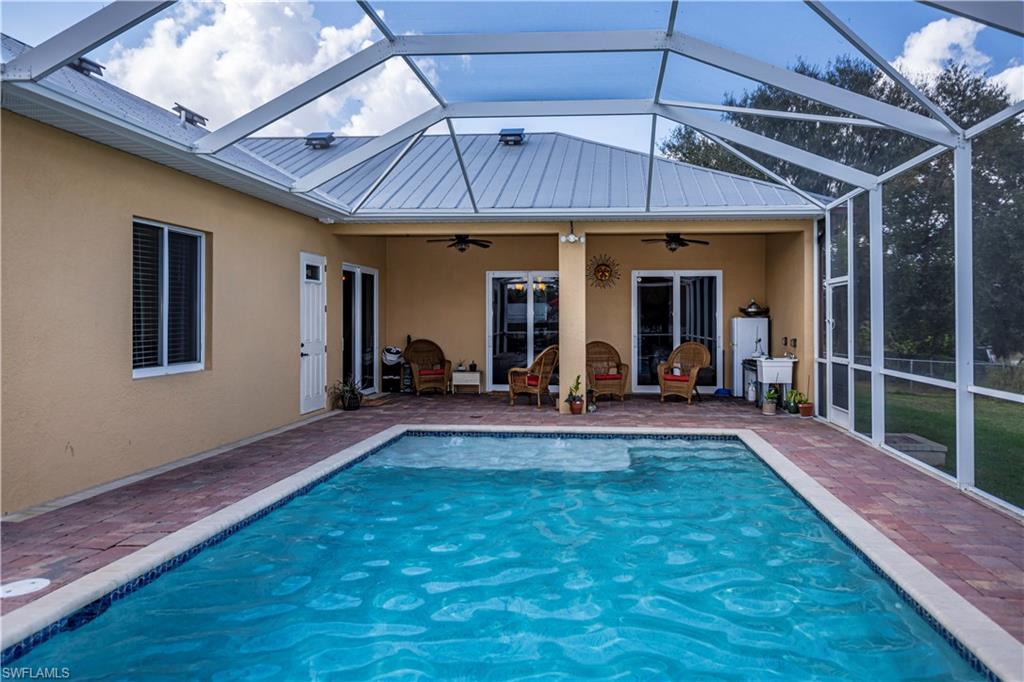 View of pool with a lanai, a patio, and ceiling fan