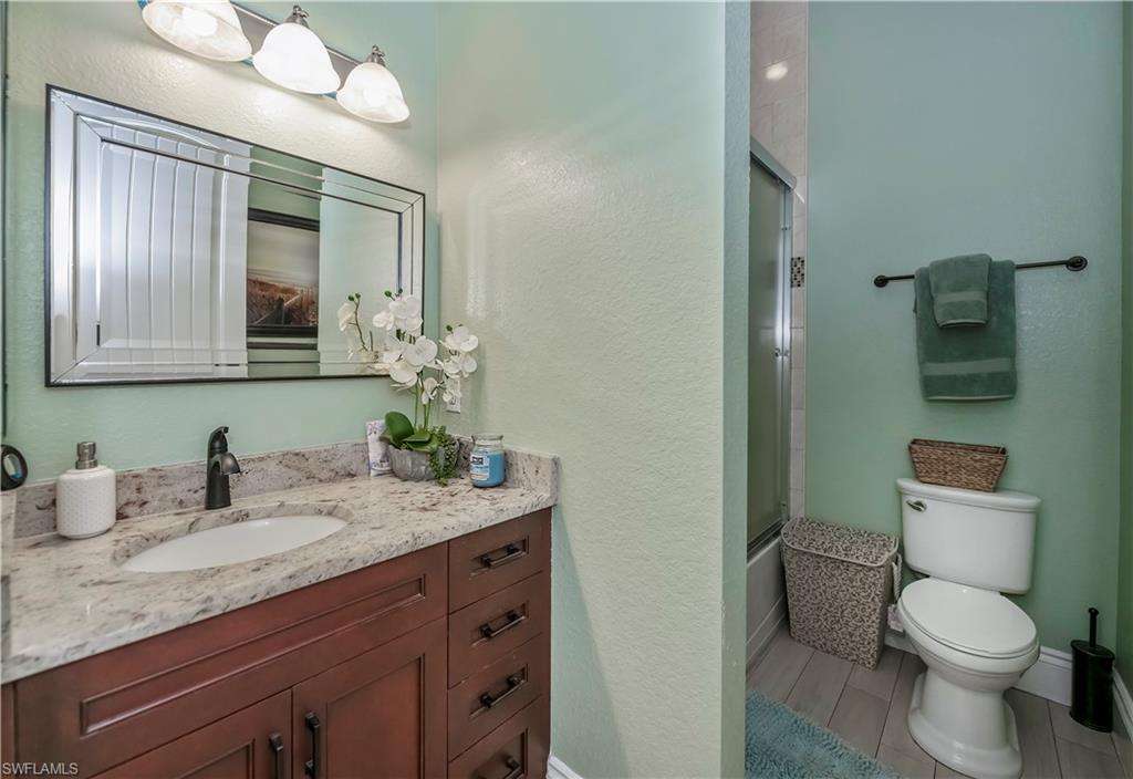 Full bathroom with vanity, shower / bath combination with glass door, and toilet