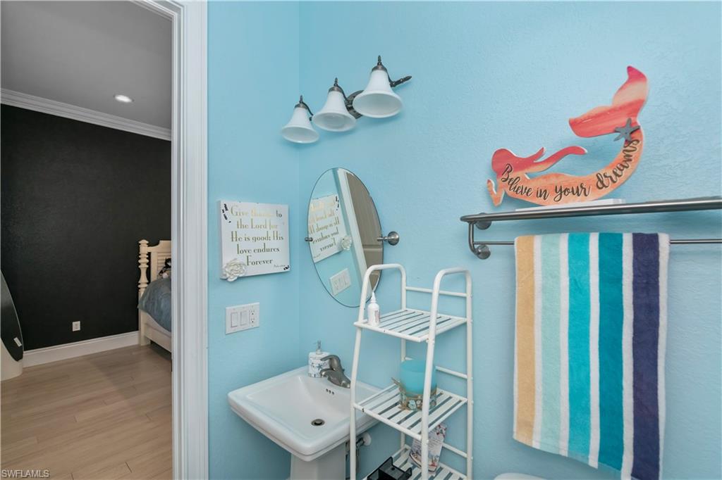 Bathroom featuring hardwood / wood-style flooring, crown molding, and sink
