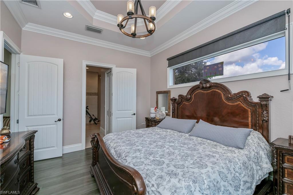Master Bedroom with a raised ceiling, crown molding, a notable chandelier, and dark hardwood / wood-style flooring