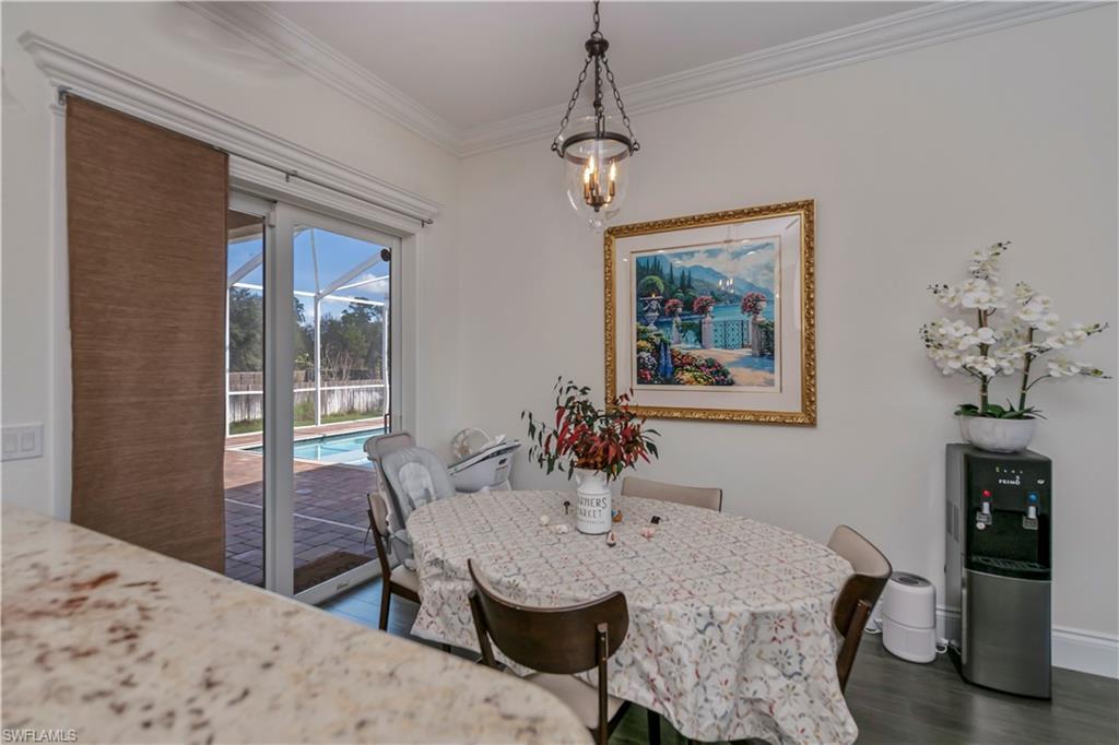 Breakfast space with crown molding, dark hardwood / wood-style floors, and an inviting chandelier