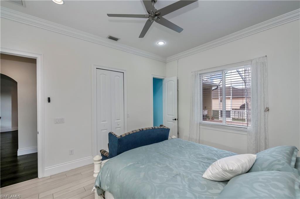 Bedroom featuring crown molding, light hardwood / wood-style flooring, a closet, and ceiling fan