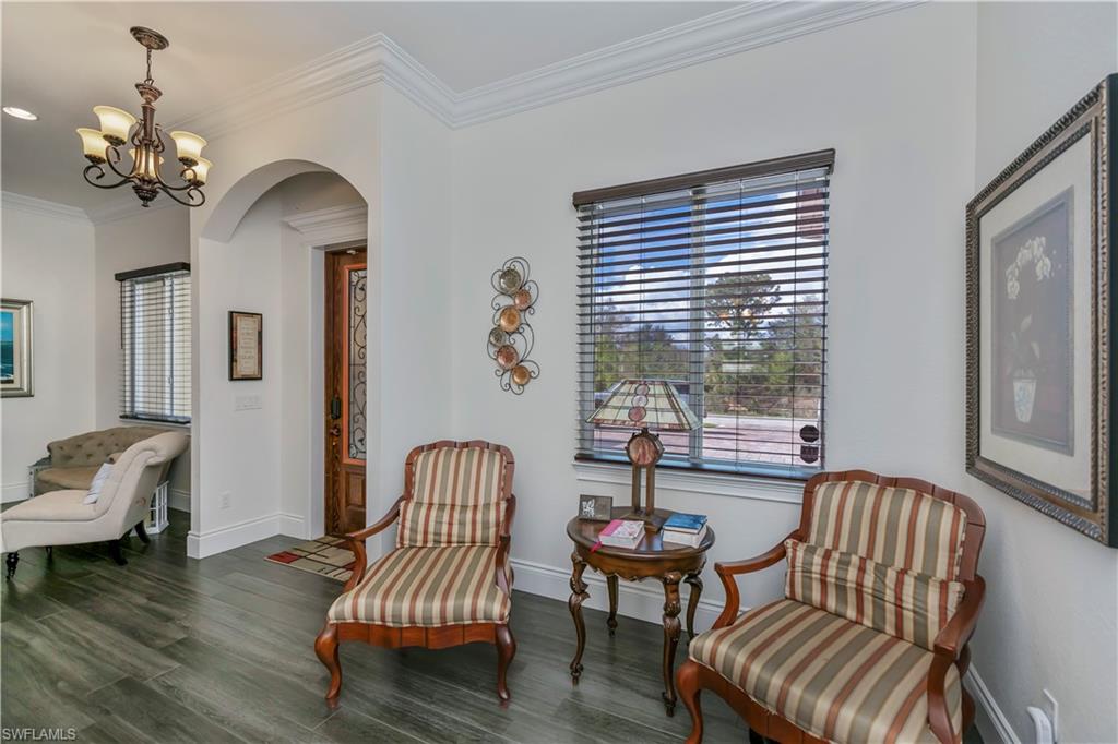 Living area with dark wood-type flooring, ornamental molding, and a notable chandelier