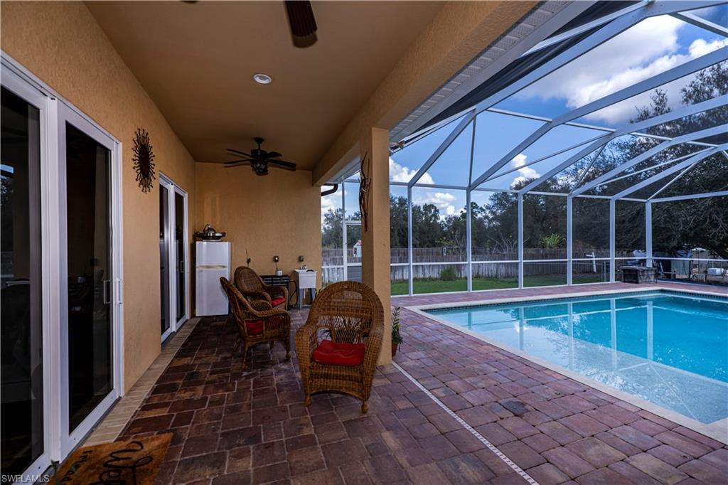 View of swimming pool with a patio, ceiling fan, and glass enclosure