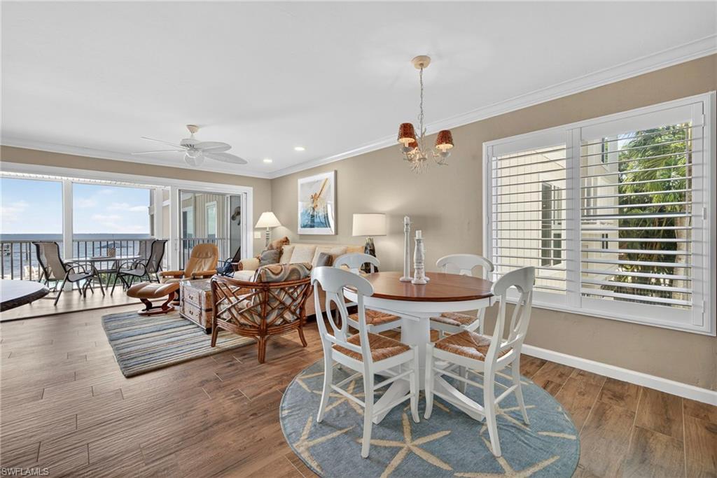 Dining area with crown molding, ceiling fan, wood finished floors, a chandelier, and recessed lighting