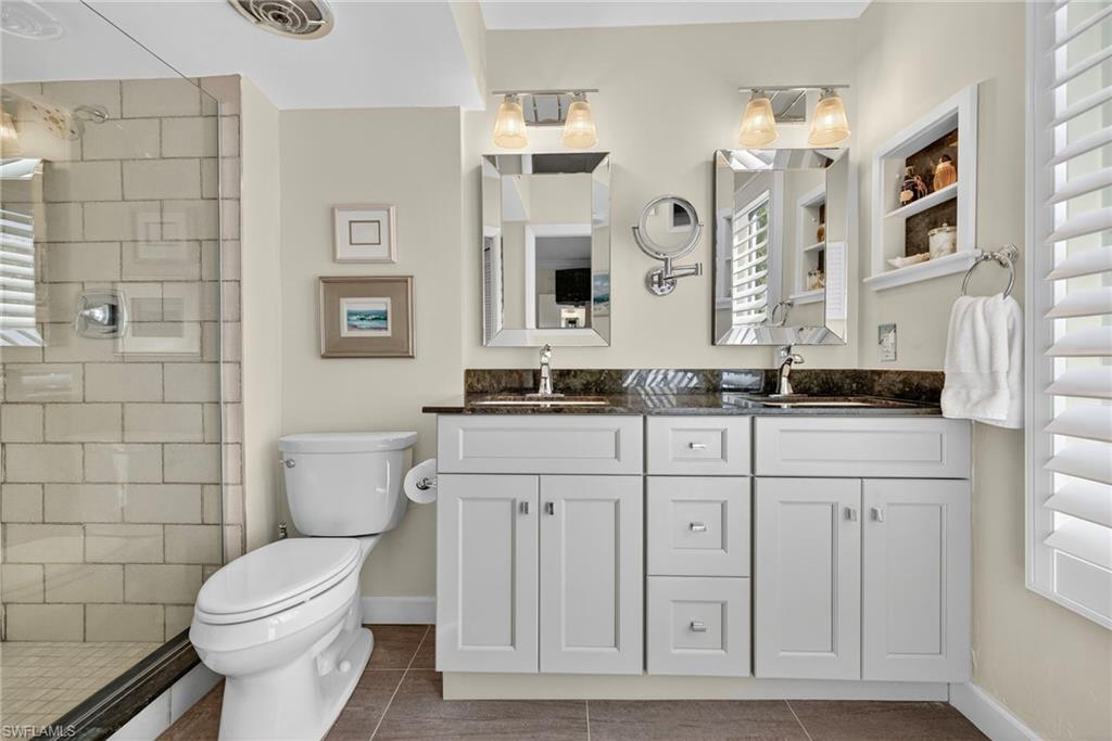 Bathroom with double vanity, dark tile patterned floors, and a stall shower