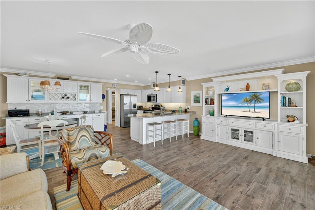 Living room featuring crown molding, light wood-style floors, and a ceiling fan