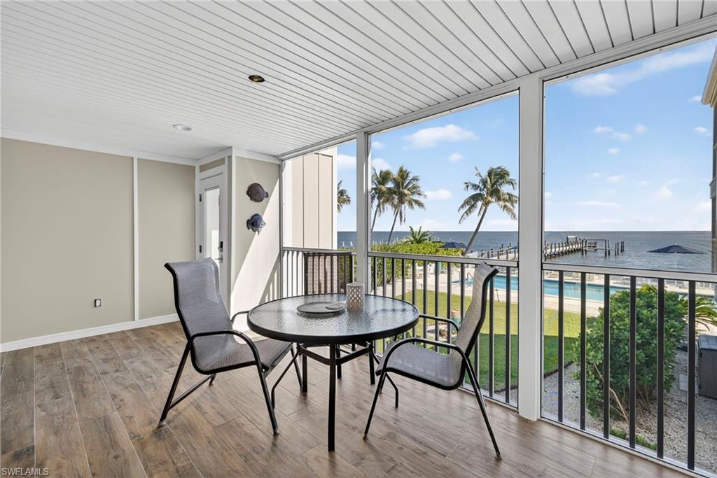 Sunroom / solarium featuring floor to ceiling windows, wood finished floors, and a water view