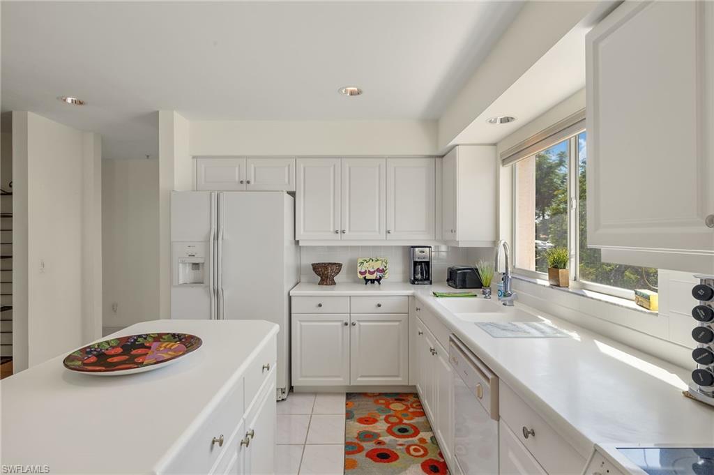 Kitchen featuring white cabinetry, white appliances, plenty of natural light, and light tile patterned floors