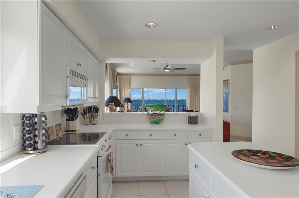 Kitchen featuring a wealth of natural light, white cabinets, white appliances, and decorative backsplash