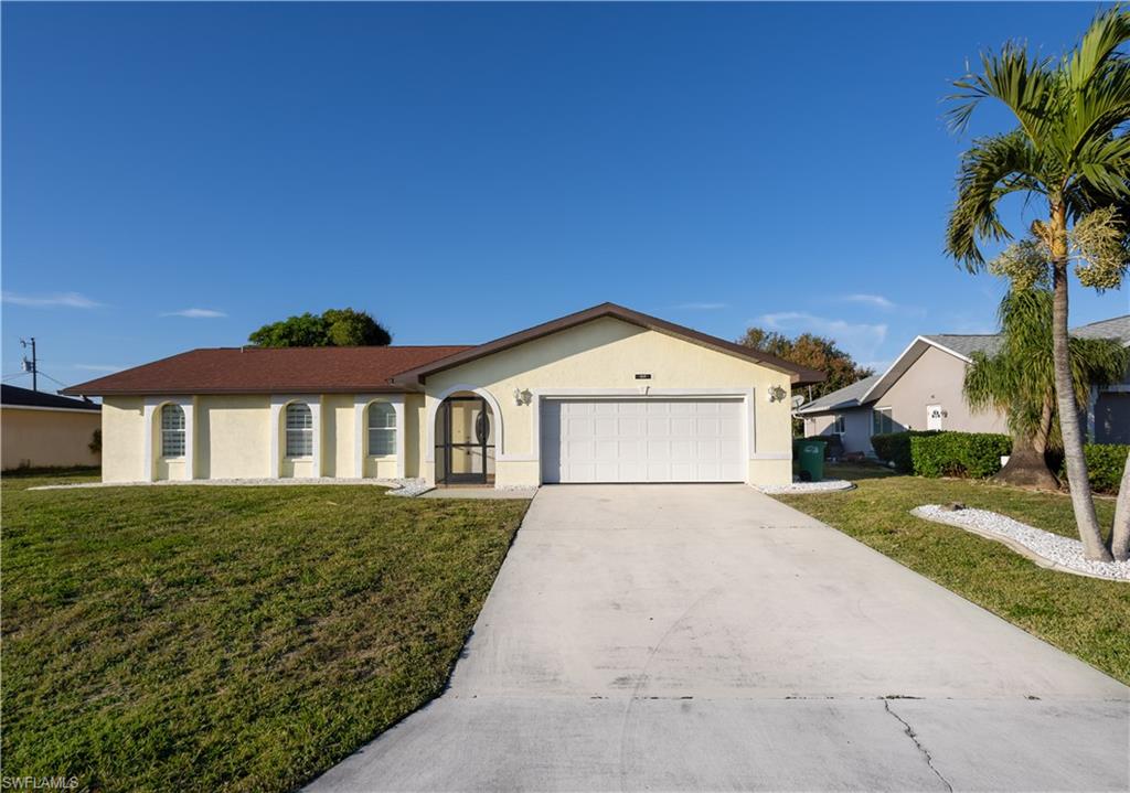 Ranch-style home featuring a garage and a front lawn