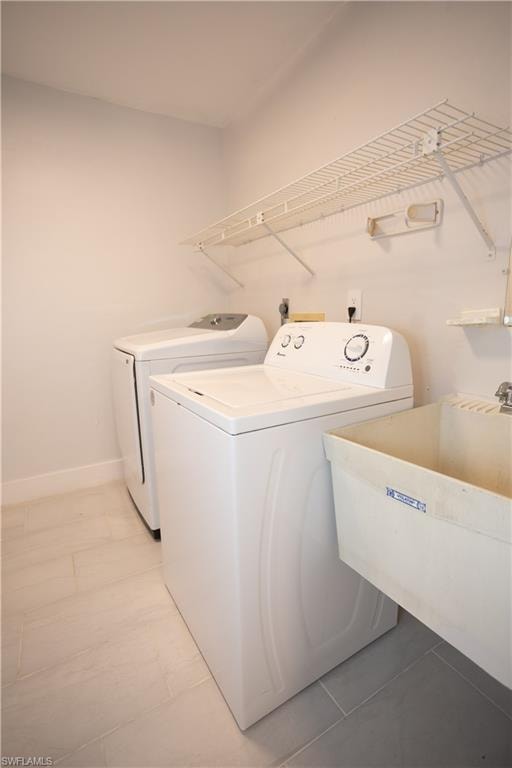 Washroom with sink, light tile patterned floors, and washer and dryer