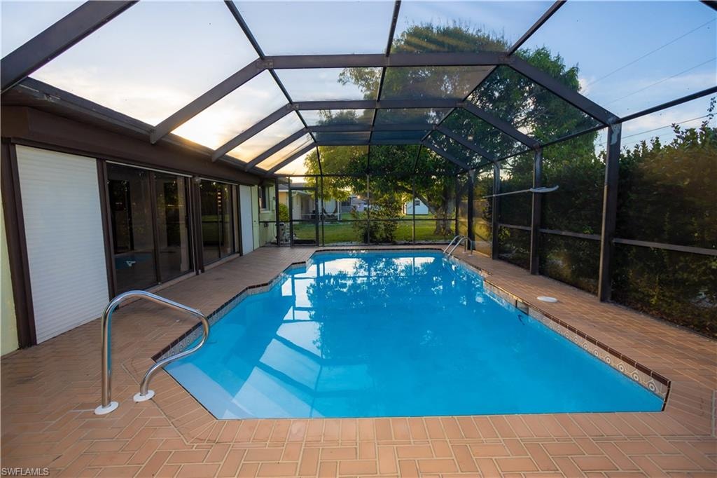 View of swimming pool featuring a patio and glass enclosure