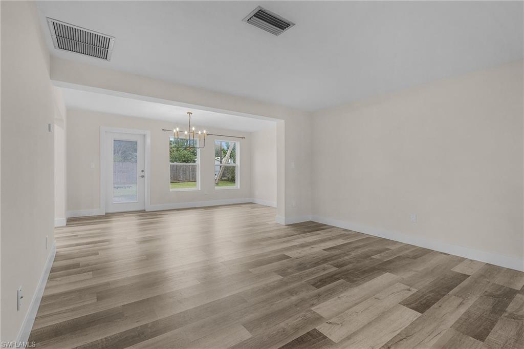 Unfurnished living room with a notable chandelier and light hardwood / wood-style floors