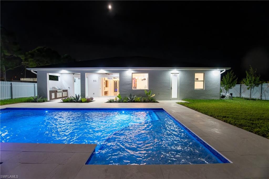 Pool at night featuring a lawn