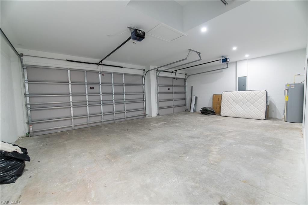 Garage featuring a garage door opener, electric water heater, and electric panel