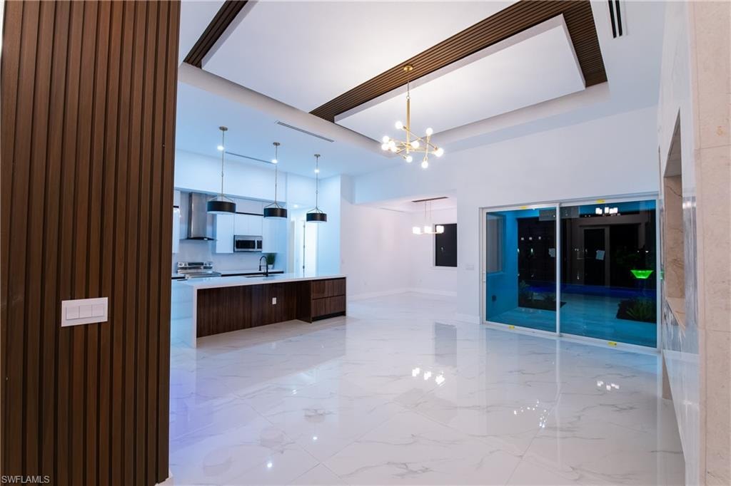 Kitchen with pendant lighting, sink, a center island, stainless steel appliances, and an inviting chandelier