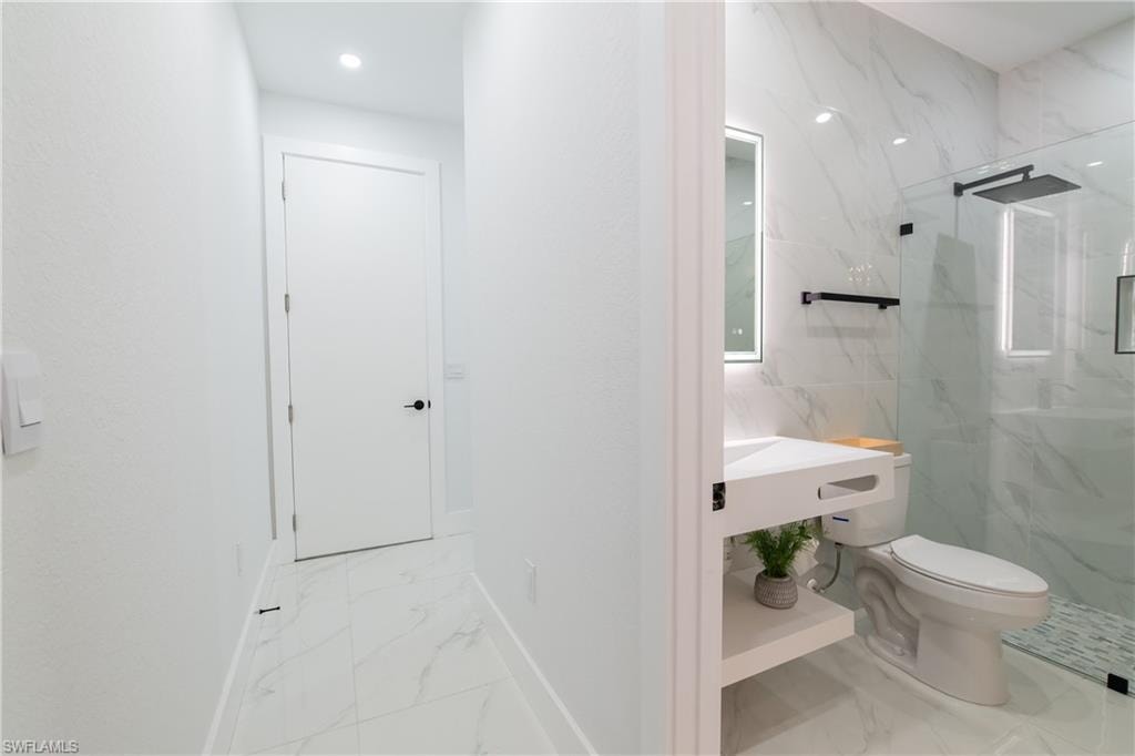 Bathroom with vanity, a shower with shower door, and toilet