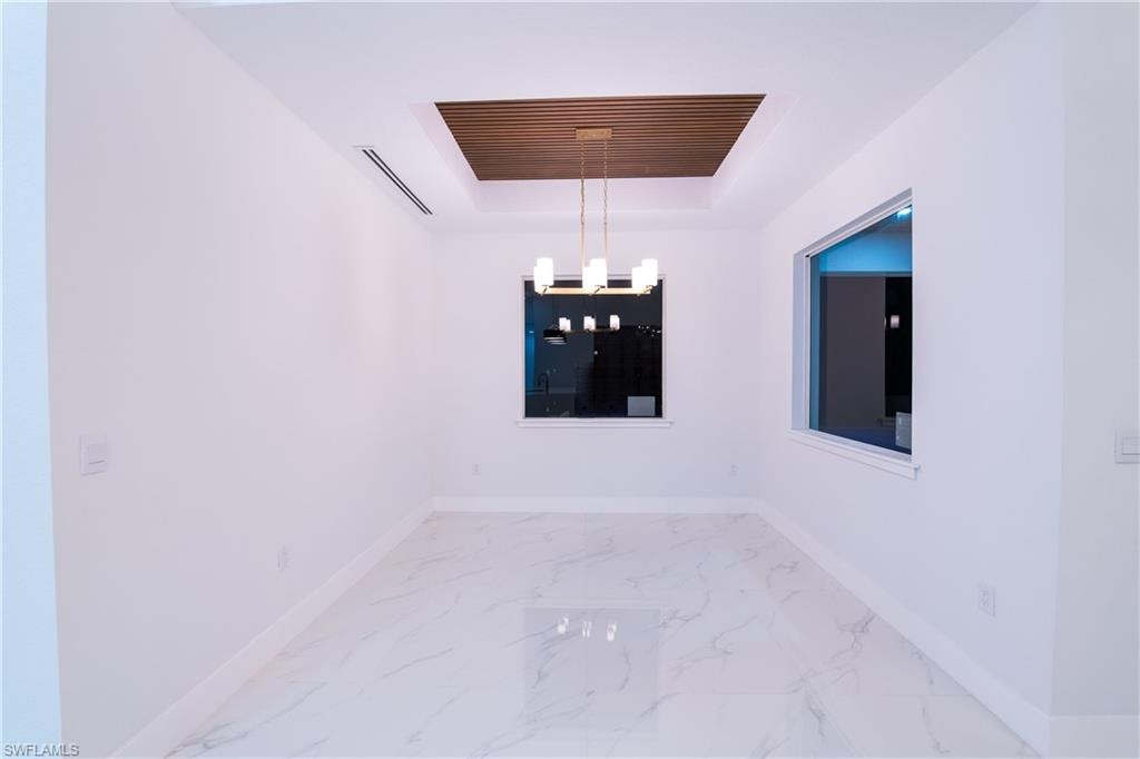 Spare room with a raised ceiling and a notable chandelier