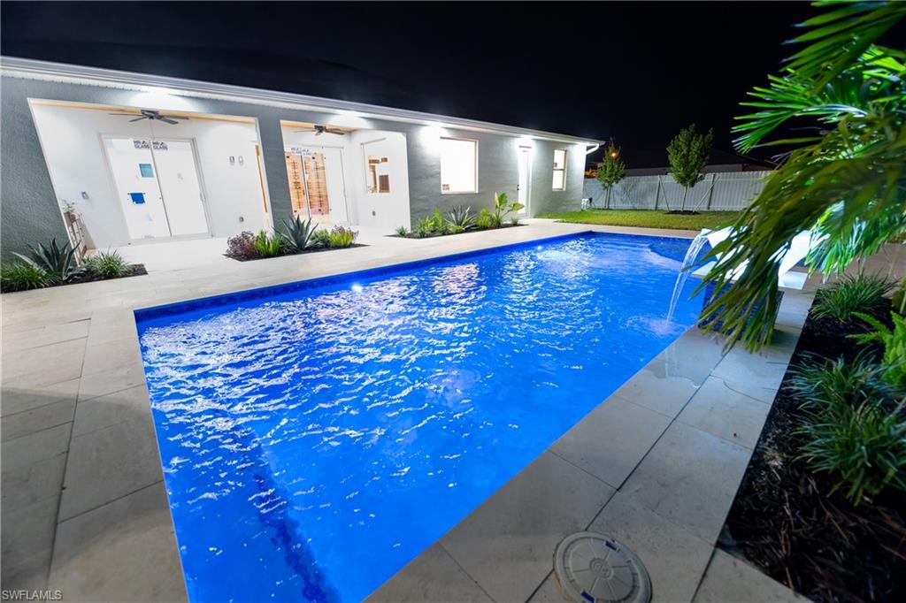 View of pool with a patio, pool water feature, and ceiling fan