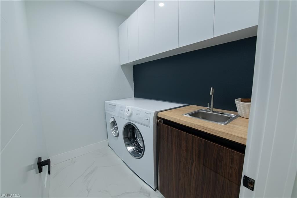 Clothes washing area featuring cabinets and sink