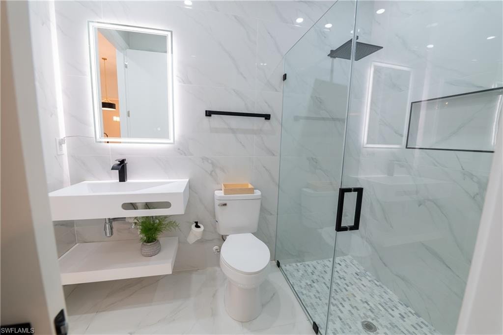 Bathroom featuring walk in shower, sink, and toilet