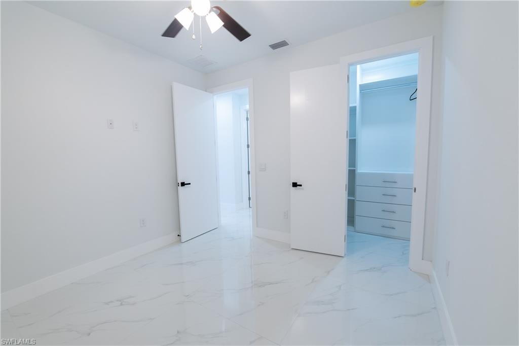 Unfurnished bedroom with ceiling fan, a spacious closet, and a closet
