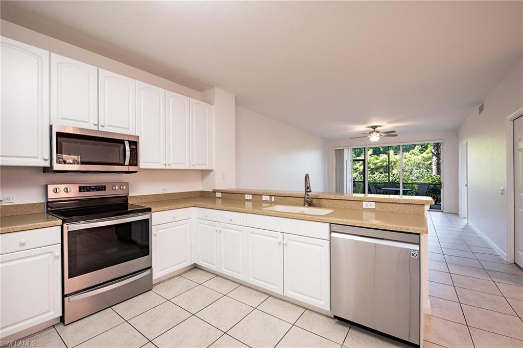Kitchen featuring sink, white cabinets, light tile patterned floors, kitchen peninsula, and stainless steel appliances